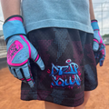 Person wearing blue and pink baseball batting gloves on a baseball field.