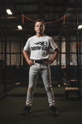 Youth baseball player wearing Throw Gas tee with arms uncrossed in indoor batting cage